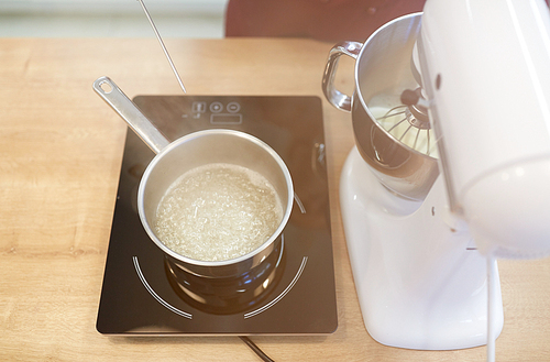 cooking, food and kitchen appliances concept - electric mixer and pot on stove