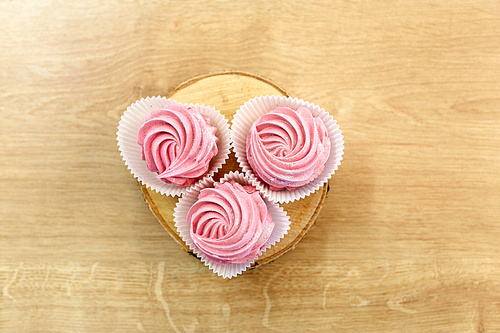 food, confection and sweets concept - zephyr, marshmallow or whipped cream on wooden stand