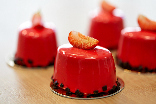 cooking, baking and food concept - strawberry mirror glaze cakes with edible gold at confectionery