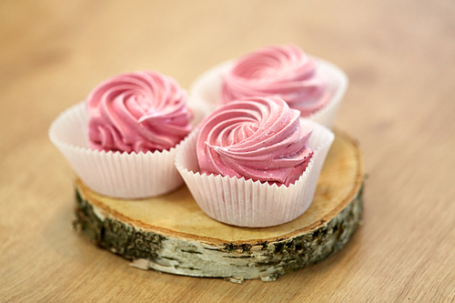 food, confection and sweets concept - zephyr, marshmallow or whipped cream on wooden stand