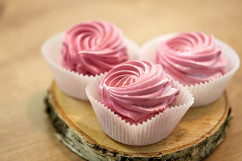 food, confection and sweets concept - zephyr, marshmallow or whipped cream on wooden stand