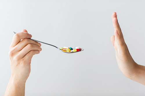 medicine, healthcare and people concept - close up of female hand holding spoon with pills