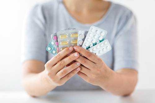 medicine, healthcare and people concept - woman hands holding packs of pills