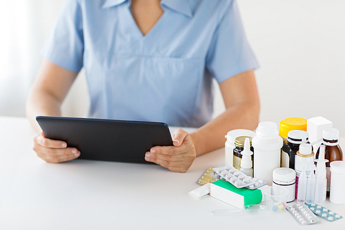 medicine, healthcare and technology concept - nurse or doctor with drugs and tablet pc computer at hospital