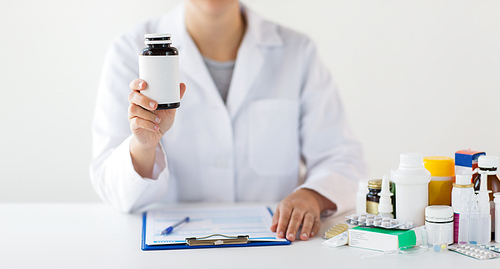 medicine, healthcare and people concept - doctor with drugs and clipboard showing jar with medication