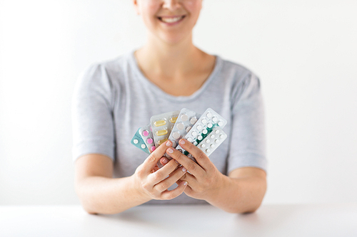 medicine, healthcare and people concept - happy woman holding packs of pills