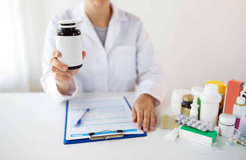 medicine, healthcare and people concept - doctor with drugs and clipboard showing jar with medication