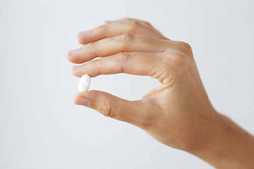 medicine, nutritional supplements and people concept - close up of hand holding pill