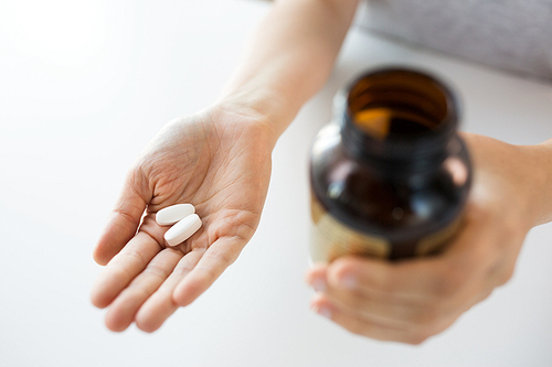 medicine, nutritional supplements and people concept - close up of hands holding pills and jar