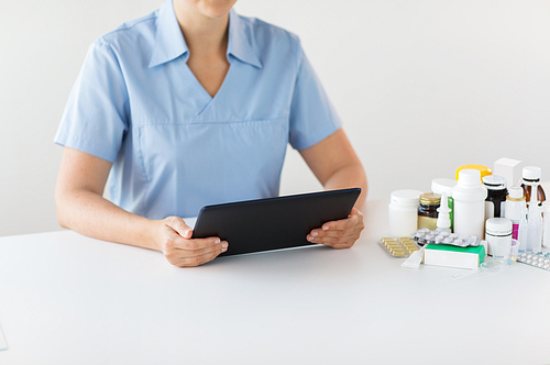 medicine, healthcare and technology concept - nurse or doctor with drugs and tablet pc computer at hospital