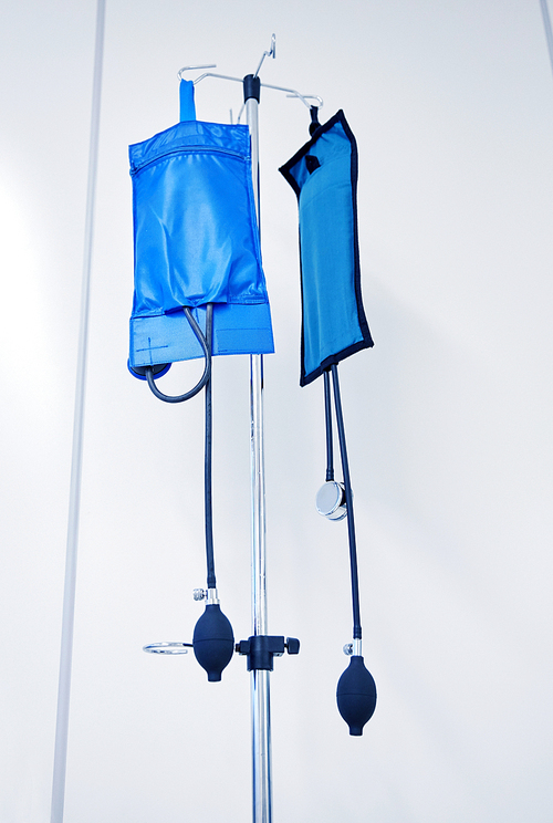 medicine, health care and medical equipment concept - two sphygmomanometers or pressure infusion cuffs hanging on holder at hospital