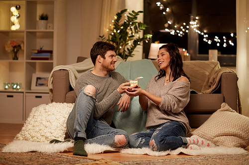 hygge, holidays and people concept - happy couple with gift box at home