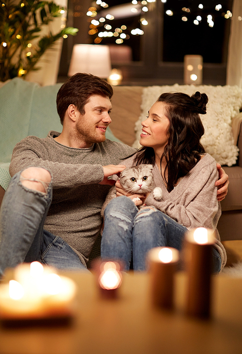 pets, hygge and people concept - happy couple with cat at home