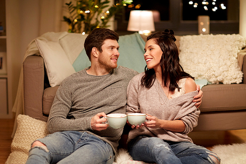hygge, leisure and people concept - happy couple drinking cacao with marshmallow at home