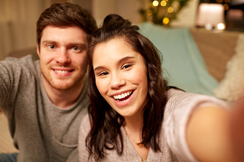 leisure and people concept - happy couple taking selfie at home