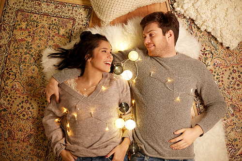 leisure, hygge and people concept - happy couple with garland at home
