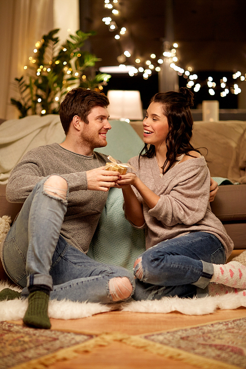 hygge, holidays and people concept - happy couple with gift box at home