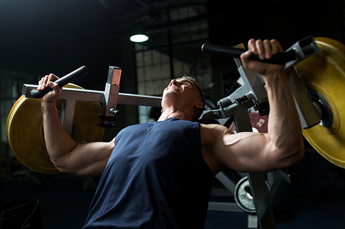 sport, fitness, bodybuilding and people concept - man doing chest press on exercise machine in gym