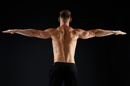sport, bodybuilding, fitness and people concept - young man or bodybuilder with bare torso over black background from back