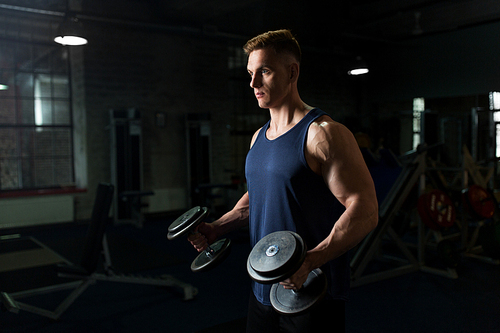 sport, bodybuilding, fitness and people concept - young man with dumbbells flexing muscles in gym