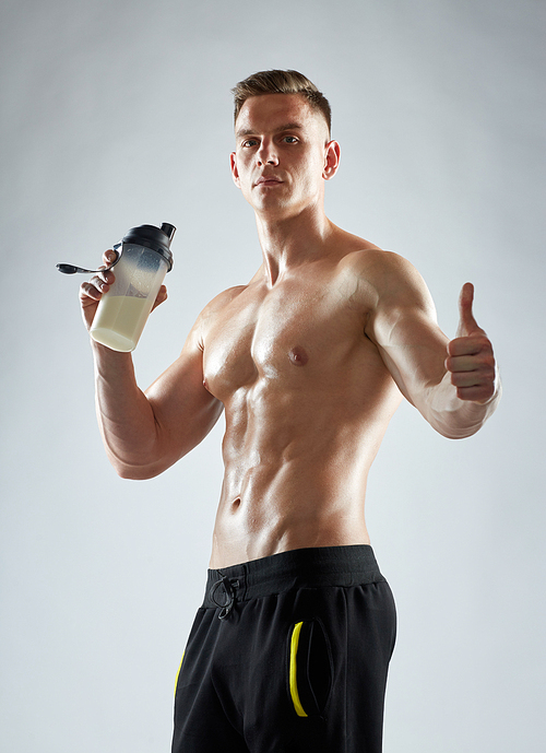sport, bodybuilding, fitness and people concept - young man or bodybuilder with protein shake bottle and bare torso showing thumbs up