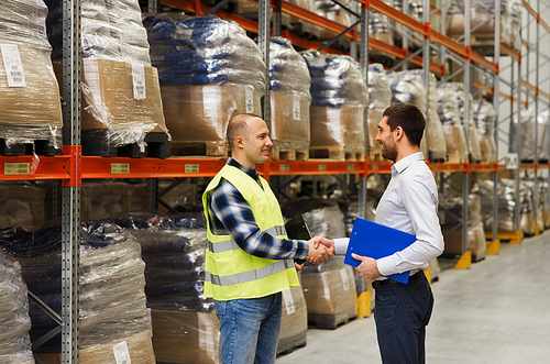 wholesale, logistic, people and export concept - manual worker and businessmen with clipboard shaking hands and making deal at warehouse