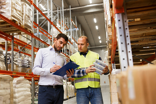 wholesale, logistic, people and export concept - manual worker and businessmen with clipboard and boxes at warehouse