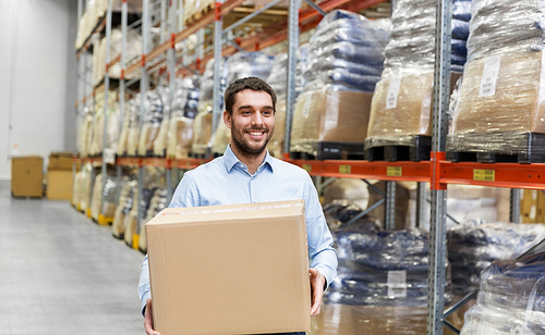 wholesale, logistic business and people concept - happy man with cardboard parcel box at warehouse
