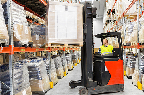 wholesale, logistic, shipment and people concept - loader operating forklift and loading boxes at warehouse