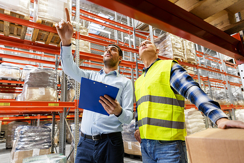 wholesale, logistic business and people concept - manual worker and businessman with clipboards at warehouse