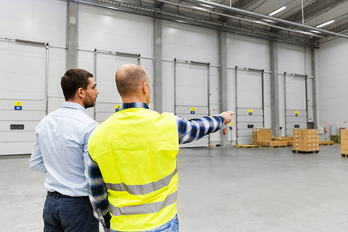 logistic business and people concept - businessman showing warehouse to worker