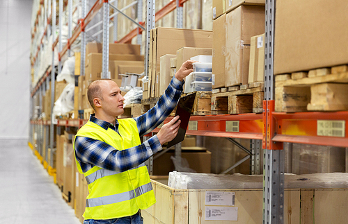 logistic business, shipment and people concept - male worker with clipboard and plastic box in reflective safety vest at warehouse
