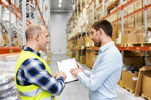 wholesale, logistic business and people concept - manual worker and businessman with clipboards at warehouse