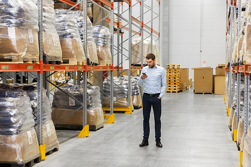 wholesale, logistic business, technology and people concept - businessman with smartphone at warehouse