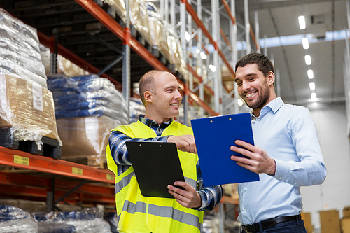 wholesale, logistic business and people concept - manual worker and businessman with clipboards at warehouse