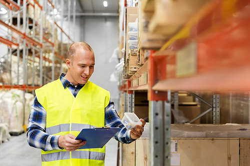 logistic business, shipment and people concept - male worker with clipboard and plastic box in reflective safety vest at warehouse