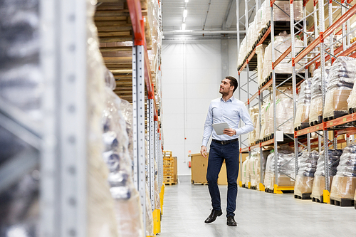 wholesale, logistic business, export and people concept - happy businessman with tablet pc computer checking goods at warehouse