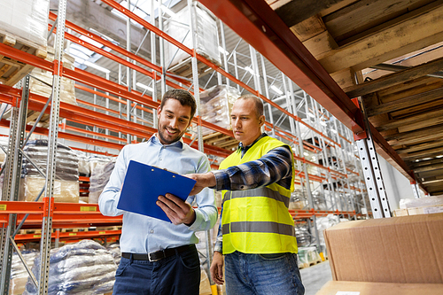 wholesale, logistic business and people concept - manual worker and businessman with clipboards at warehouse