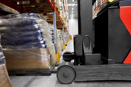logistic business and shipment concept - close up of forklift loading goods at warehouse