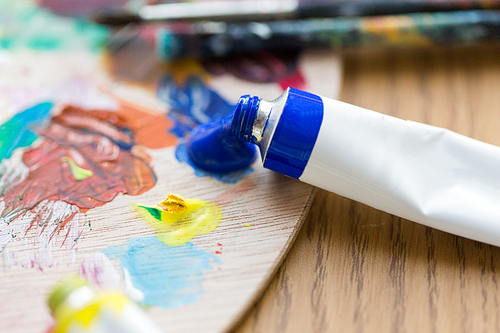 fine art, creativity, painting and artistic tools concept - close up of acrylic color or paint tube and palette