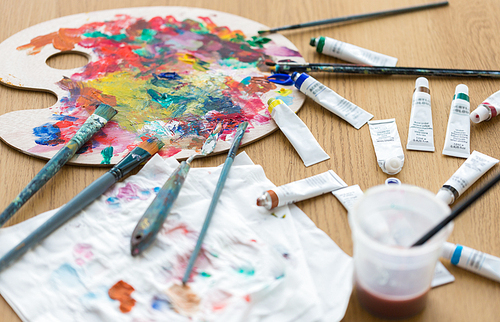 fine art, creativity and artistic tools concept - palette, brushes and paint tubes on table