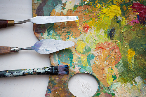 fine art, creativity and artistic tools concept - close up of palette knives or painting spatulas and paintbrush from top