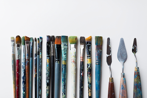 fine art, creativity and artistic tools concept - palette knives or painting spatulas and paintbrushes from top