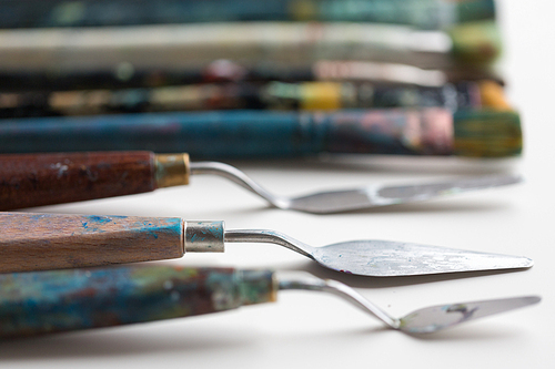 fine art, creativity and artistic tools concept - palette knives or painting spatulas and paintbrushes