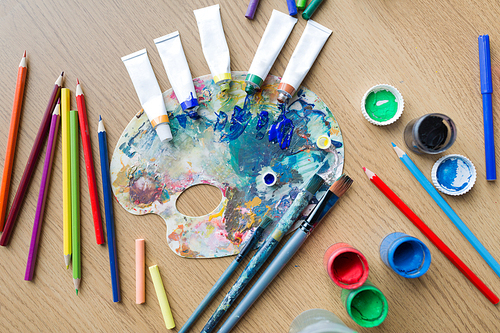 fine art, creativity and artistic tools concept - palette, brushes, paint tubes and gouache colors on table