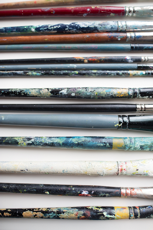 fine art, painting, creativity and artistic tools concept - close up of dirty paintbrushes from top
