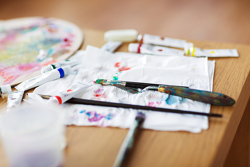 fine art, creativity and artistic tools concept - palette knife, brushes, paint tubes and paper tissue on table