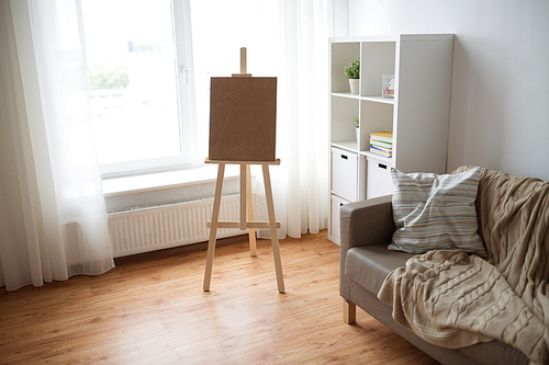 fine art, creativity and artistic tools concept - wooden easel at home room or studio