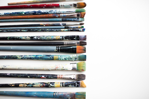 fine art, painting, creativity and artistic tools concept - dirty paintbrushes from top