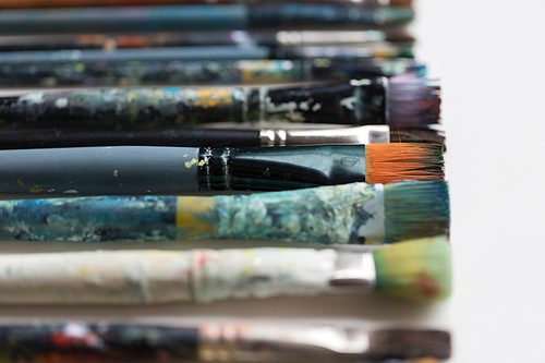 fine art, painting, creativity and artistic tools concept - close up of dirty paintbrushes